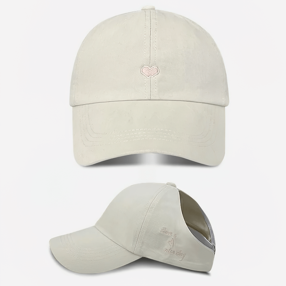 Cream cotton baseball cap with adjustable strap and subtle heart logo, perfect for casual attire. Stylish and versatile for all seasons.